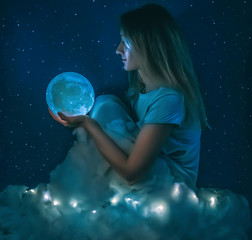 Naklejka premium Young pretty woman with the full moon and clouds on the starry blue background closeup
