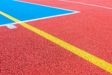 Colorful sports court background. Top view to red and blue field rubber ground with white and yellow lines outdoors