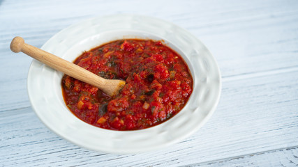 Classic homemade tomato sauce in a white plate on a white wooden table Tomatoes with parsley Tomato pasta sauce close up