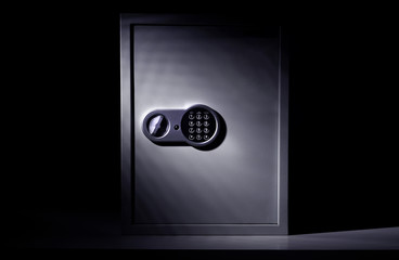 Strongbox steel safe with digital combination code lock on a dark background with falling light