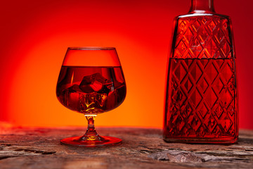 glass of whiskey with bottle on wooden table , red tint atmosphere, time of relax with whisky