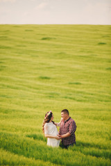 waiting baby. Parenthood. Pregnant young woman and her husband are happy to hold hands, going in the outdoor in the field of green grass background. selective focus.
