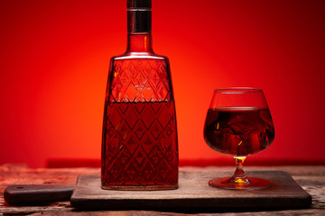 glass of whiskey with bottle on wooden table , red tint atmosphere, time of relax with whisky