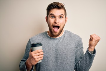 Young blond man with beard and blue eyes drinking cup of coffee over white background screaming proud and celebrating victory and success very excited, cheering emotion