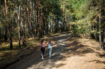 Obraz premium Two girls of the athlete perform a run in the morning in the sunny forest
