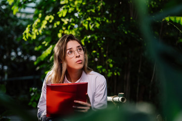 Fototapeta premium Young female agricultural engineer working in greenhouse.