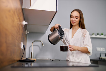 attractive young lady pours coffee into a cup, she is going to drink it in the morning. every morning begins from coffee