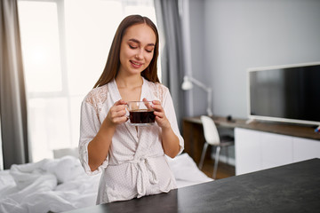 cute young woman drinking coffee at home, she wakes up with hot coffee in the morning