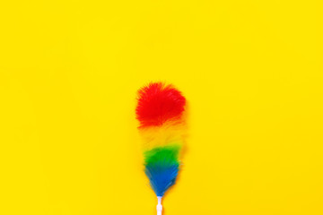 Colorful feather duster on yellow background. Cleaning concept.