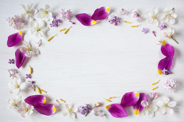 Petals of tulips, apple flowers, lilac flowers on a white wooden background. Space for text.