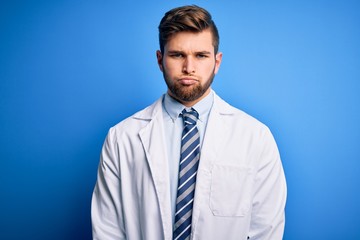 Young blond therapist man with beard and blue eyes wearing coat and tie over background depressed and worry for distress, crying angry and afraid. Sad expression.