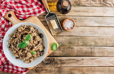 Homemade traditional Italian mushroom risotto on rustic wooden background. Classic Risotto with mushrooms served on a white plate