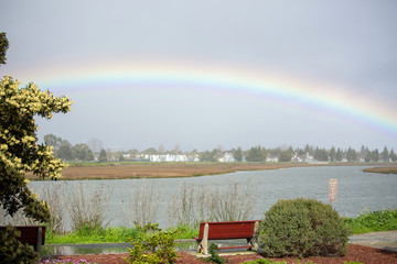 Rainbow over the lake. Quiet walkway with a bench and a view of the rainbow. Time to stop and enjoy the natural phenomenon