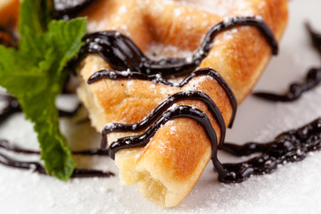 Belgian waffles in powdered sugar with chocolate syrup and mint