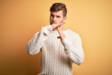 Young blond man with beard and blue eyes wearing white sweater over yellow background Doing time...