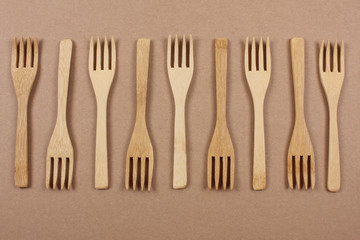 Wooden forks. Eco friendly disposable kitchenware utensils on paper background. Eco friendly concept. Top view. Copy space.