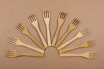 Wooden forks. Eco friendly disposable kitchenware utensils on paper background. Eco friendly concept. Top view. Copy space.