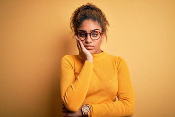 Fototapeta na wymiar Young beautiful african american girl wearing sweater and glasses over yellow background thinking looking tired and bored with depression problems with crossed arms.