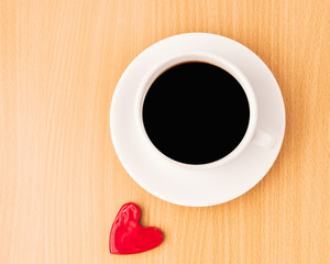 flat lay of cup of black coffee on wooden table with red mini heart, top view, drinking coffee in the morning concept