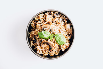 Homemade italian risotto with mushrooms and parmesan cheese in a dark bowl on a white background.