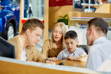 helpful consultant have conversation with customers while sitting at table, clients think about making purchase in their dealership