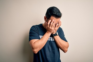 Handsome man with beard wearing t-shirt with volunteer message over white background with sad...