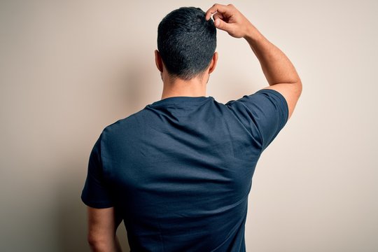 Handsome man with beard wearing t-shirt with volunteer message over white background Backwards thinking about doubt with hand on head