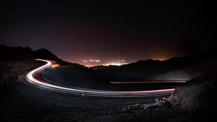 Afwasbaar Fotobehang Snelweg bij nacht highway long exposure vehicle light trails curvy highway between mountains at starry night 