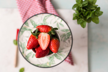 Overhead view of a bowl full of red strawberries on a floral green elegant dish.