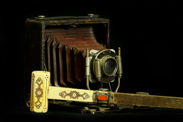 Old bellows camera, chrome plated brass, stick with onyx handle, on a black background