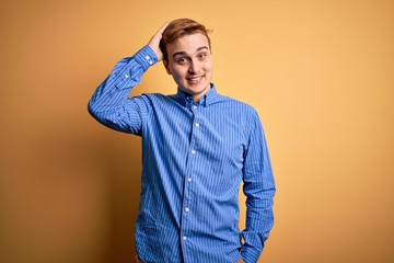 Young handsome redhead man wearing casual striped shirt over isolated yellow background confuse and wonder about question. Uncertain with doubt, thinking with hand on head. Pensive concept.