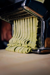 Making green spinach tagliatelle in a machine..Close-up