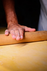 The chef kneads the dough with a wooden rolling pin..Preparation for cooking pasta