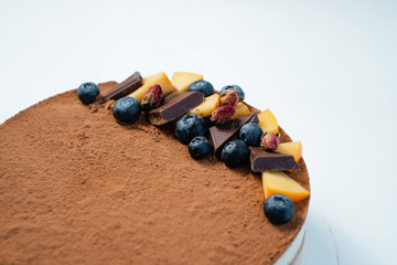 Delicious tart with fresh blackberry, chocolate and currants on the white table. Side view