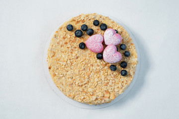 Delicious cake with fresh blackberry, nuts and pink hearts on the white table. top view horizontal