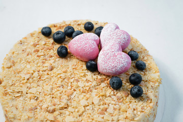 Delicious cake with fresh blackberry, nuts and pink hearts on the white table. close up
