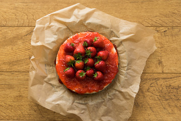 Homemade cheesecake with strawberries in the middle of a wooden table