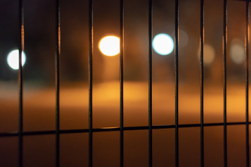 Out of focus city lights behind a fence. Bokeh. Soft focus. Night city colorful street lights