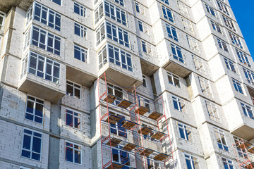 Extensive scaffolding providing platforms for work in progress on a new apartment block,Tall building under construction with scaffolds,Freestanding tower crane on a building site