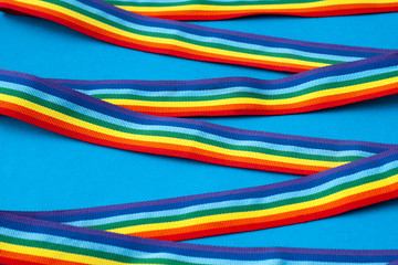 crossed rainbow ribbons and awareness ribbon on a blue background