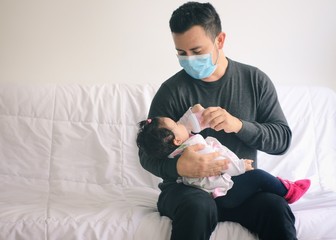 Padre alimentando a su bebé con un biberón en la cuarentena por COVID 19. Día del padre en cuarentena.