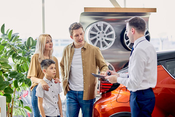 Fototapeta na wymiar adorable family get keys by car in dealership, affable confident consultant give long-awaited keys to clients