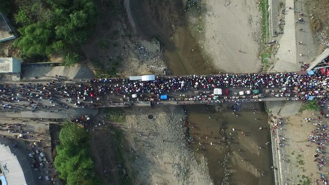 Huge crowd of people cross bridge over Massacre river. Dominican Republic
