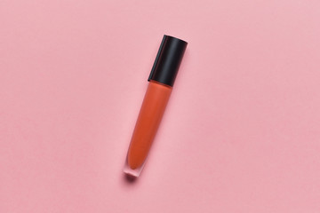 Tube with liquid lipstick on a pink background with a top view