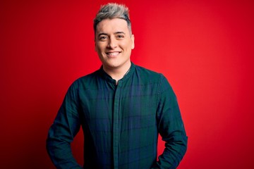 Obraz premium Young handsome modern man wearing elegant green shirt over red isolated background with a happy and cool smile on face. Lucky person.