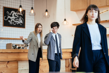 Two coworkers Staring and Gossiping About Their Female Colleague