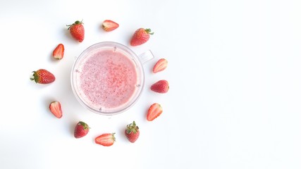 Vista superior. Jarra con jugo de freza rodeado por frutas de frezas en una mesa blanca. Espacio en blanco para texto. Espacio de copia