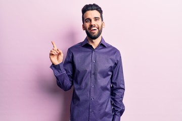Fototapeta premium Young handsome man with beard wearing casual shirt with a big smile on face, pointing with hand finger to the side looking at the camera.