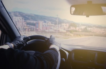 Fototapeta premium Manos con guantes quirúrgicos sosteniendo el volante. Hombre conduce el automóvil durante la pandemia por Covid-19. Transporte durante la cuarentena.