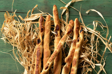 Breadsticks grissini with raisins on a green wood background.